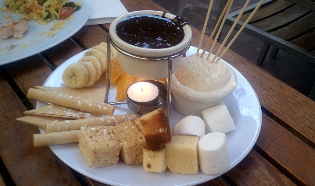 Comer fondue envolve todo um ritual, desde a escolha da panela certa até a maneira de degustá-lo. Tradicionalmente, utiliza-se um garfo longo para mergulhar os pedaços de pão no queijo derretido, e existem algumas regras de etiqueta a serem seguidas. Reprodução: Flipar