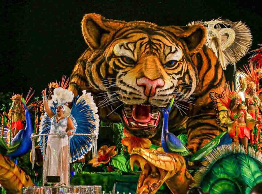 Por fim, outra escultura característica em abre-alas é o tigre da Unidos do Porto da Pedra, escola de São Gonçalo. Muitas agremiações costumam utilizar o seu símbolo: águia, tigre, leão, coroa, entre outros, na primeira alegoria.  Reprodução: Flipar
