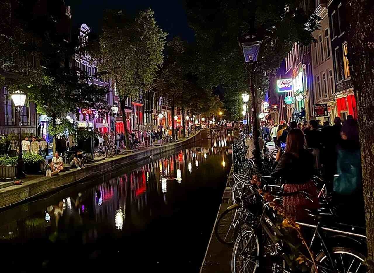 Red Light District (De Wallen) - Descrição: O bairro mais famoso de Amsterdã, conhecido por suas vitrines iluminadas em vermelho, tem uma história que remonta ao século XIV. Hoje, é uma área regulamentada e culturalmente significativa - Localização: Centro de Amsterdã - Referências Históricas: De Wallen é um dos distritos mais antigos e preservados da cidade Reprodução: Flipar