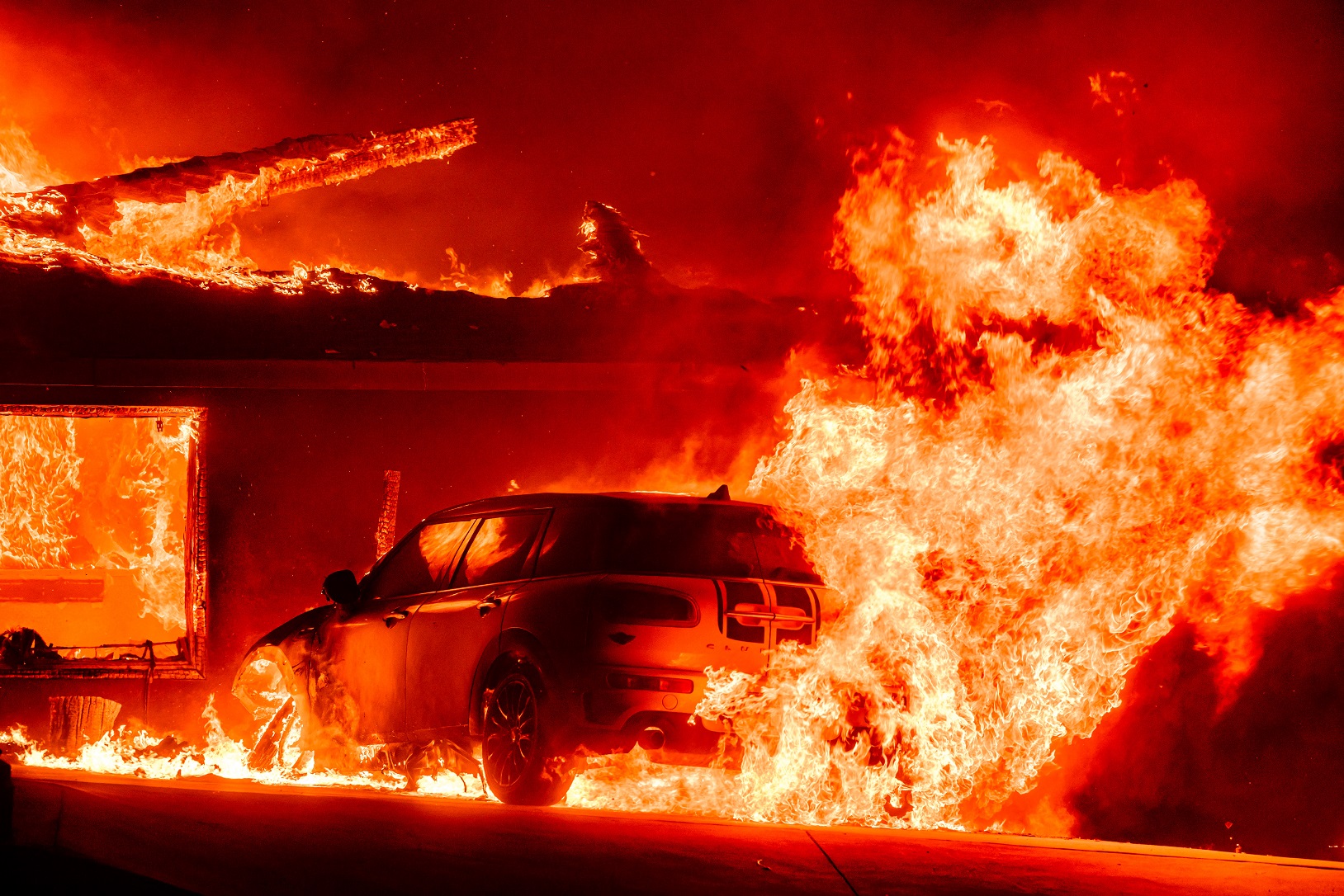 Um carro e uma casa queimam durante o incêndio de Eaton na área de Altadena, no Condado de Los Angeles, Califórnia, em 8 de janeiro de 2025 Josh Edelson/AFP