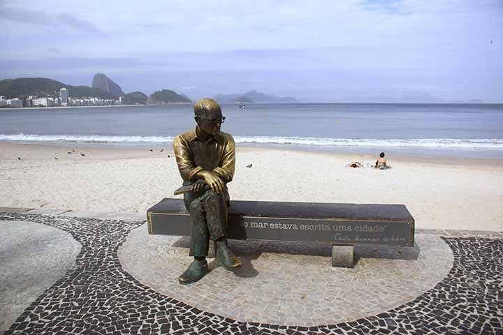 Em 2002, foi instalado na altura do Posto 6 uma estátua em homenagem ao poeta Carlos Drummond de Andrade. Pesando cerca de 150 quilos, a estátua se tornou mais um símbolo icônico do bairro, com o escritor sentado de pernas cruzadas de costas para o mar e o horizonte da praia de Copacabana. Reprodução: Flipar