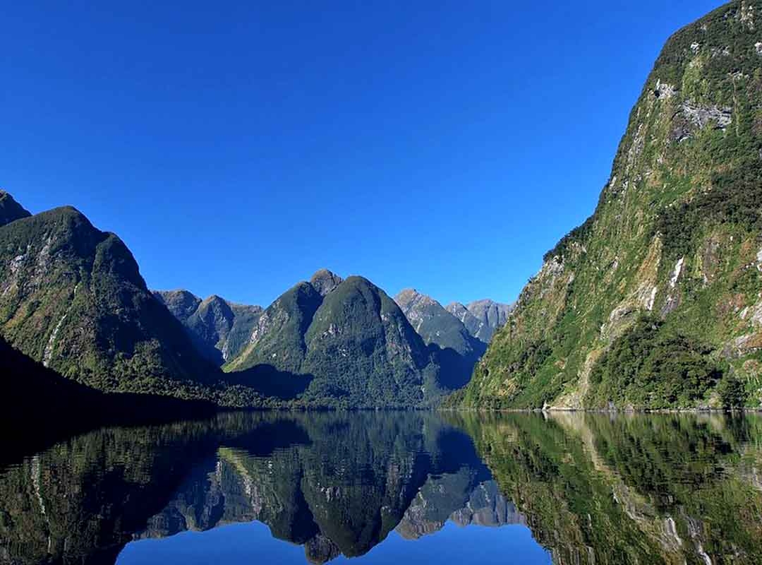 Fiorde Doubtful Sound- Nova Zelândia -  Localizado no oeste do país, no Mar da Tasmânia , tem 40 km de extensão e atinge 421m de profundidade. A região tem chuvas abundantes e na margem   do fiorde ficam densas florestas tropicais com vegetação que contrasta com a origem gélida do fiorde. Reprodução: Flipar