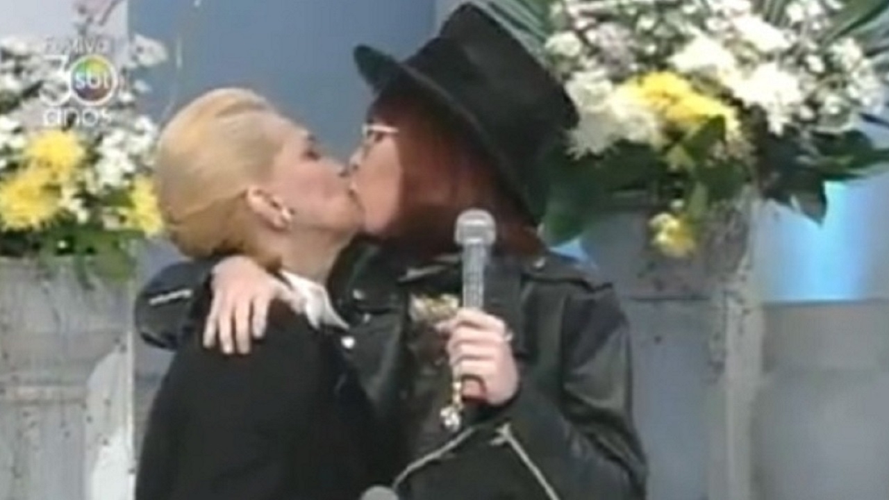 De forma inesperada e bem-humorada, Rita aproximou-se e deu um beijo nos lábios da apresentadora. O gesto inaugurou uma marca registrada na trajetória de Hebe. A partir dali, ela seria repetida com inúmeros convidados ao longo dos anos.
. Foto: Reprodução: Flipar