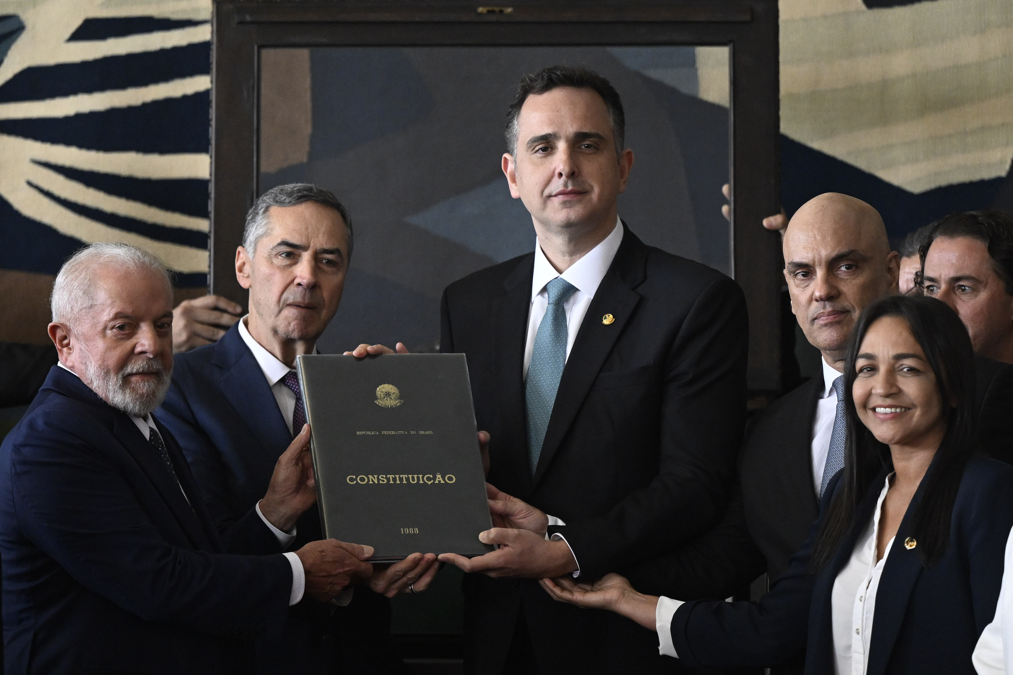 8 de janeiro - O presidente Luiz Inácio Lula da Silva, o presidente do Supremo Tribunal Federal, Luis Roberto Barroso, o presidente do Senado, Rodrigo Pacheco, e o então presidente do Tribunal Superior Eleitoral, Alexandre de Moraes, seguraram uma constituição brasileira durante um evento para marcar a consolidação da democracia no Brasil, um ano depois que apoiadores do ex-presidente de extrema direita Jair Bolsonaro invadiram o palácio presidencial, o Congresso e o Supremo Tribunal, em Brasília. Mateus Bonomi/Anadolu via Getty Images