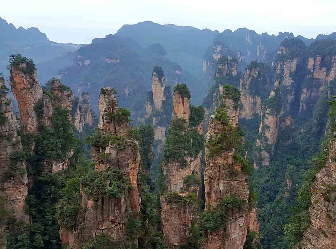 Zhangjiajie, China: Essas formações são mundialmente famosas por sua beleza e singularidade. Localizado na província de Hunan, o Parque Nacional de Zhangjiajie é conhecido por suas colunas de pedra de quartzito que se erguem verticalmente da terra, criando um cenário de tirar o fôlego. Reprodução: Flipar