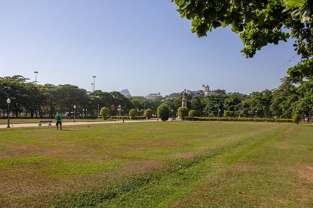O Brasil também abriga praças belíssimas que combinam história, arquitetura e/ou paisagens deslumbrantes. Entre elas, a Praça Paris, no bairro carioca da Glória, que fica no Aterro do Flamengo com a histórica Igreja da Glória ao fundo, mostrada na foto. Começamos por ela.  Reprodução: Flipar