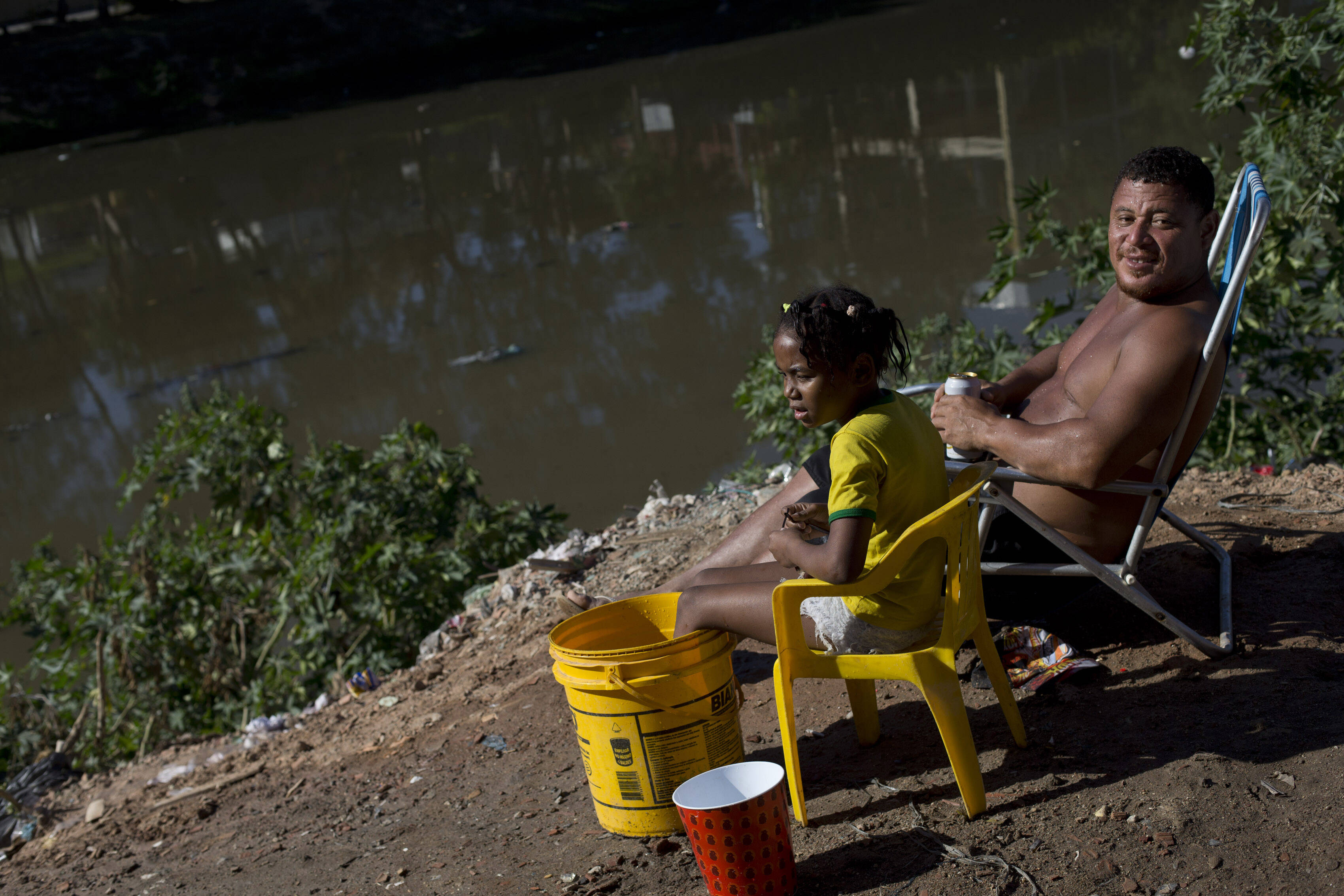 Morador da favela Mandela toma sol à beira de um rio com água contaminada. Foto: Silvia Izquierdo/AP
