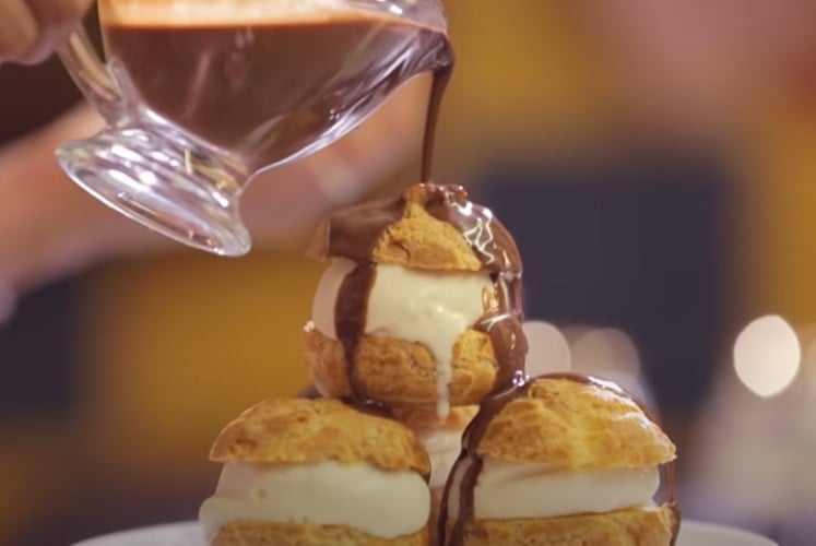Profiteroles - Pequenos bolinhos recheados com creme de confeiteiro e cobertos com chocolate derretido, uma sobremesa clássica da culinária francesa Reprodução: Flipar