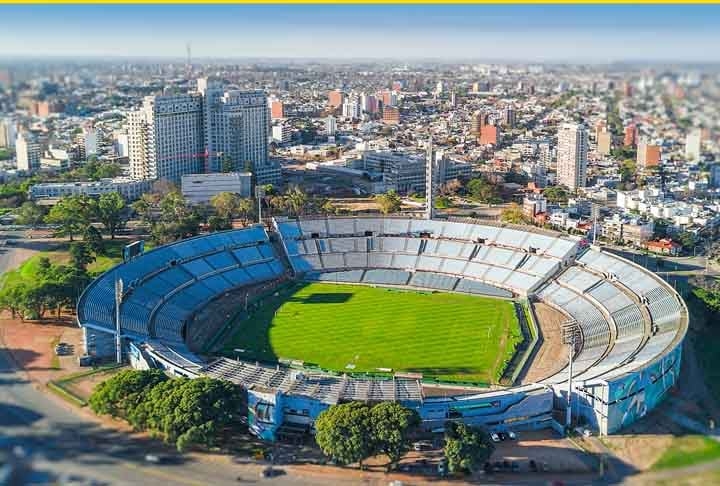 O Estádio Centenário é localizado em Montevidéu. Com capacidade para 65.235 espectadores, é onde joga normalmente a seleção uruguaia de futebol. Construído para sediar a primeira edição da Copa do Mundo, em 1930, foi inaugurado com atraso devido às chuvas em 18 de Julho daquele ano, com o jogo Uruguai 1 x 0 Peru.  Reprodução: Flipar