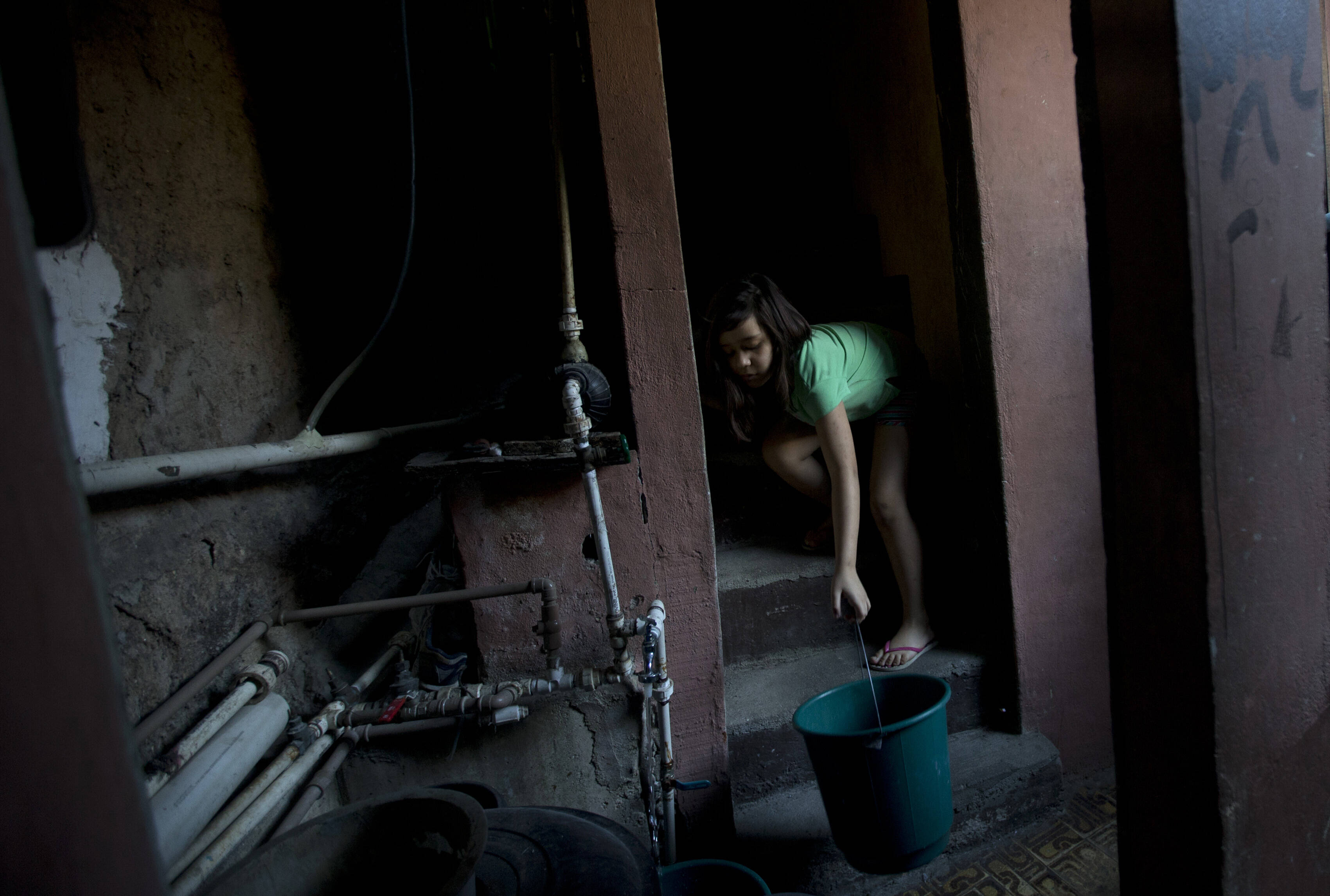 Mulher enche baldes de água tratada por moradores na favela da Rocinha. Foto: Silvia Izquierdo/AP
