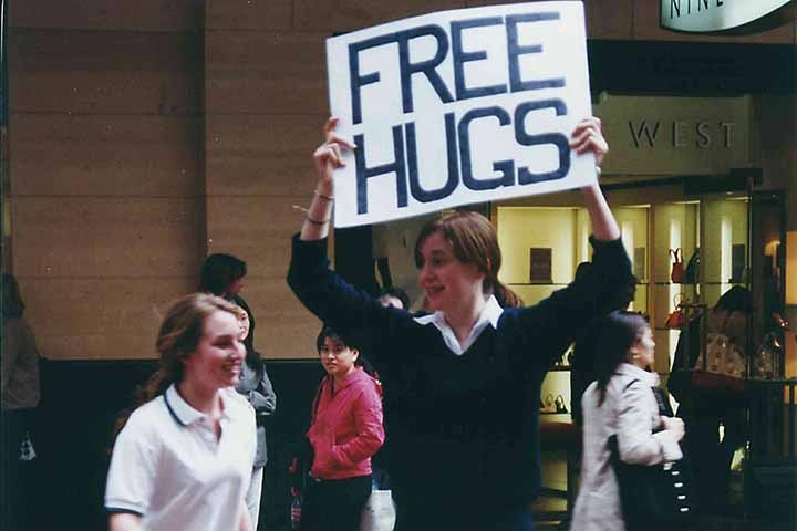 Em um shopping da capital de Nova Gales do Sul, ele decidiu distribuir abraços em estranhos a fim de disseminar afeto e promover uma visão coletiva de mundo. 
 Reprodução: Flipar