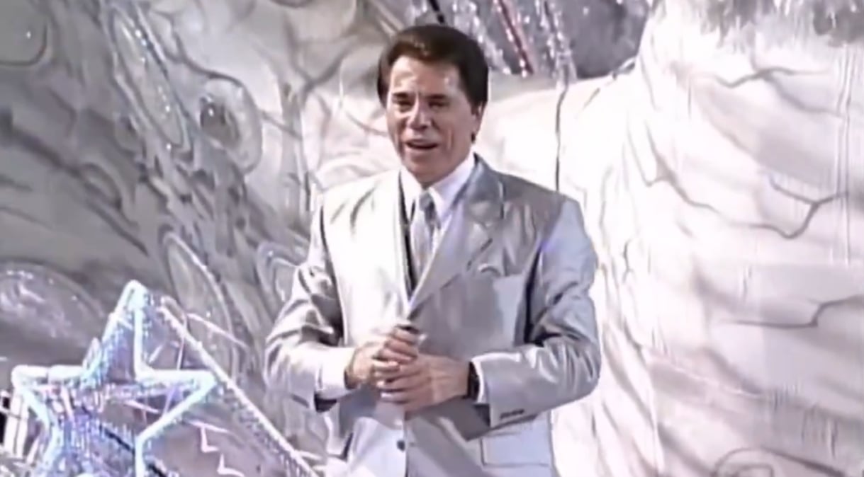 Silvio Santos é uma das figuras mais populares na televisão brasileira. E também surpreendente. Fora da tela desde 2022, Silvio volta e meia chama atenção.  No carnaval de 2024, por exemplo, o SBT surpreendeu o público ao exibir um desfile de escola de samba que homenageou Silvio Santos, há 23 anos.  Reprodução: Flipar