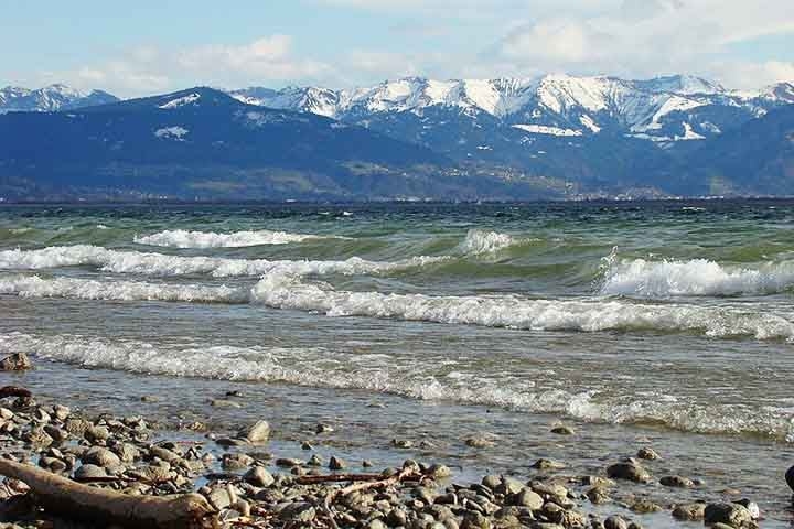 O entorno do lago é um espetáculo à parte, com uma paisagem que combina montanhas suaves, colinas e extensas áreas agrícolas, além de pequenas cidades históricas e vilarejos pitorescos. Reprodução: Flipar
