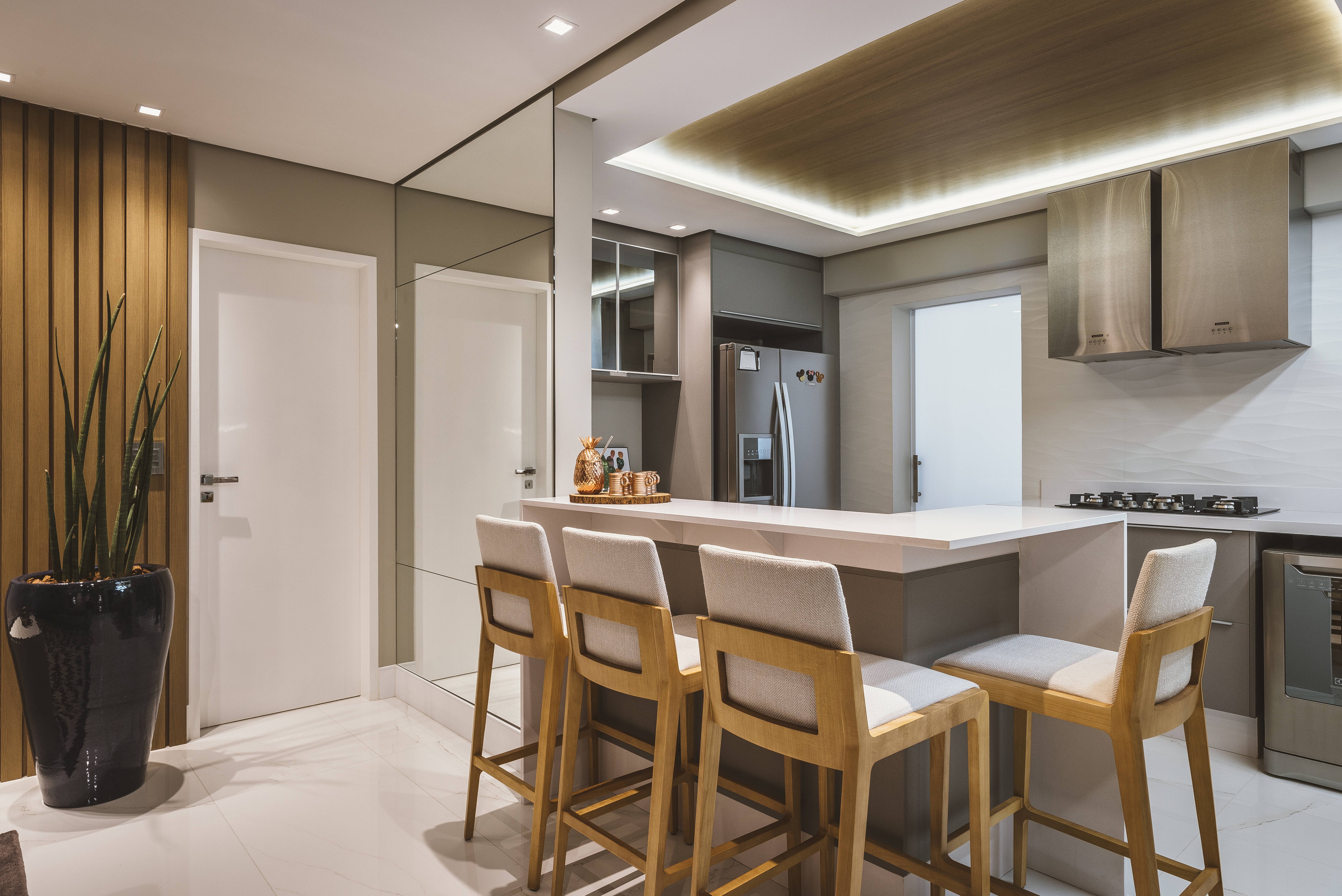 Os materiais de madeira trabalhados na cozinha e sala de jantar se contrastam de forma harmoniosa com o branco. Foto: Henrique Ribeiro/Meet Arquitetura