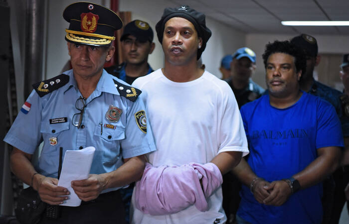 Ronaldinho Gaúcho e o irmão Assis chegaram algemados para depoimento. O ex-jogador enrolou uma camisa nas mãos. Foto: Reprodução/ Twitter
