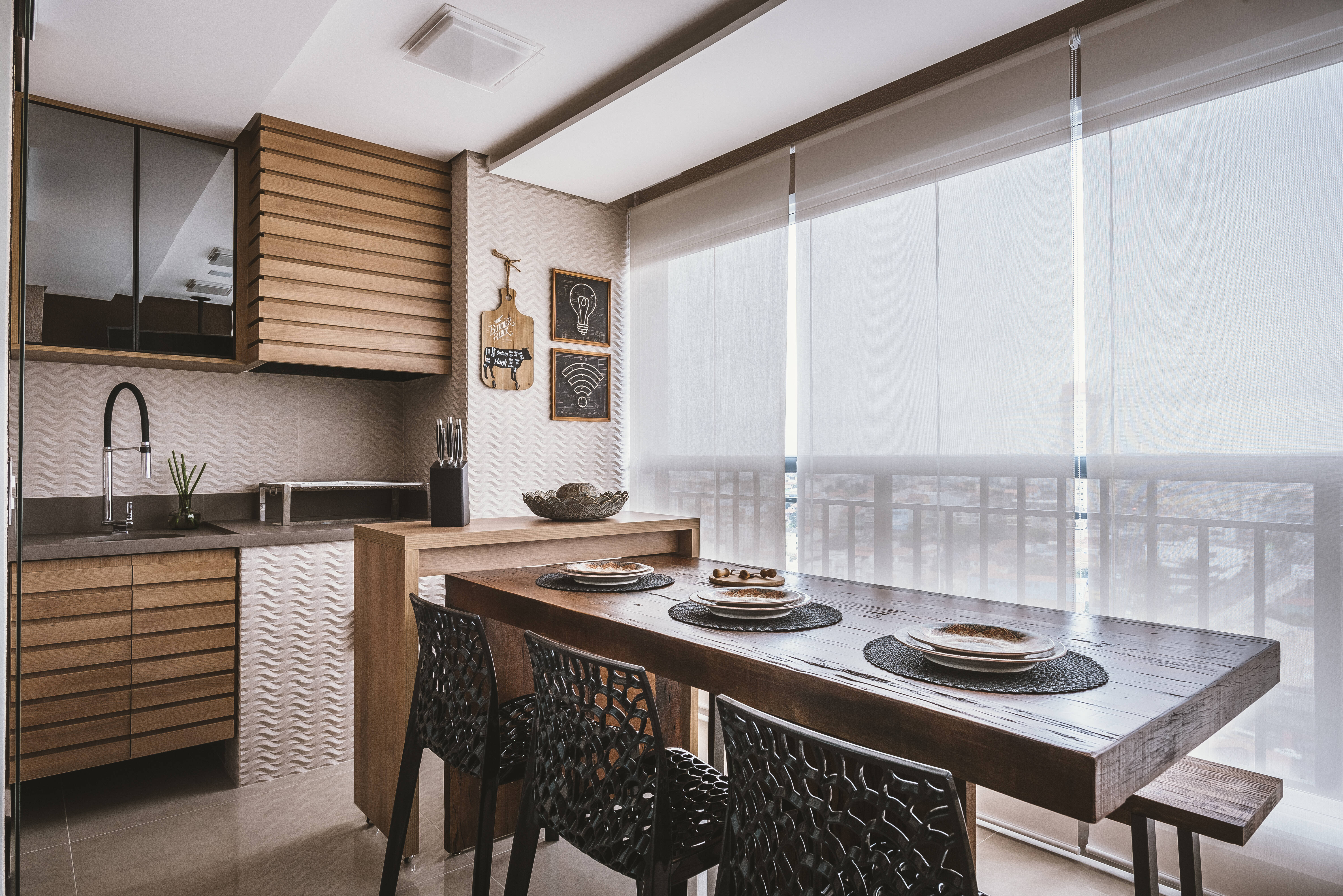 Esta cozinha se integra com a sala de jantar e é trabalhada em tons fechados, conferindo elegância ao espaço. Foto: Henrique Ribeiro/Meet Arquitetura
