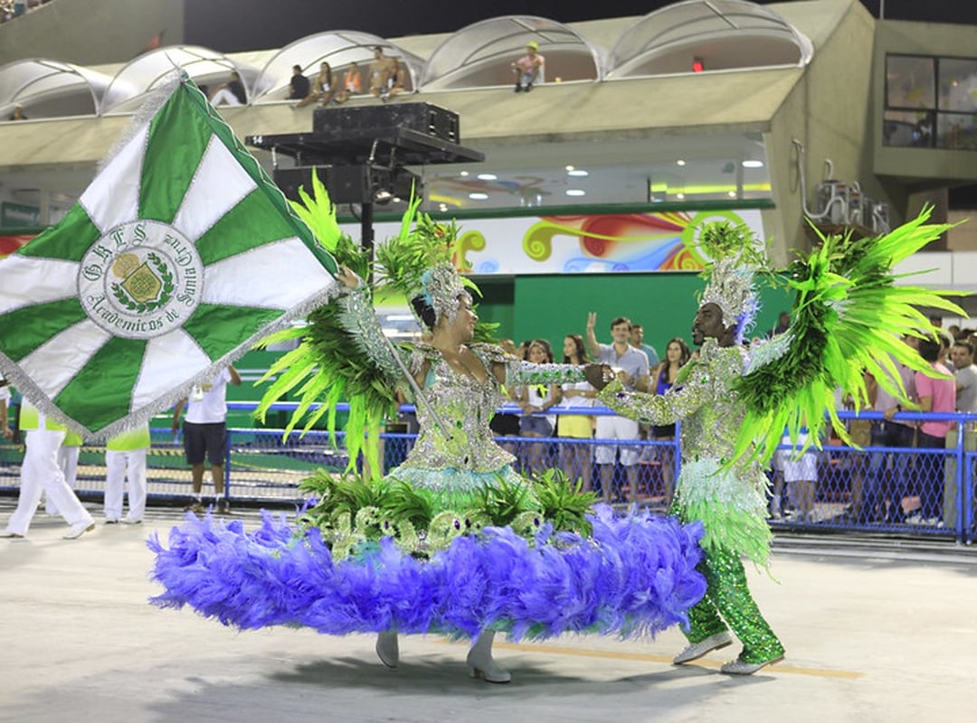 A função de mestre sala e porta-bandeira têm a dança inspirada no minueto, de origem francesa. Ainda no período de escravidão, os negros espiavam as danças e replicavam os passos no ritmo do batuque africano. A dança de proteção surgiu, portanto, com a criatividade dos negros, assim como o samba que se conhece hoje.  Reprodução: Flipar