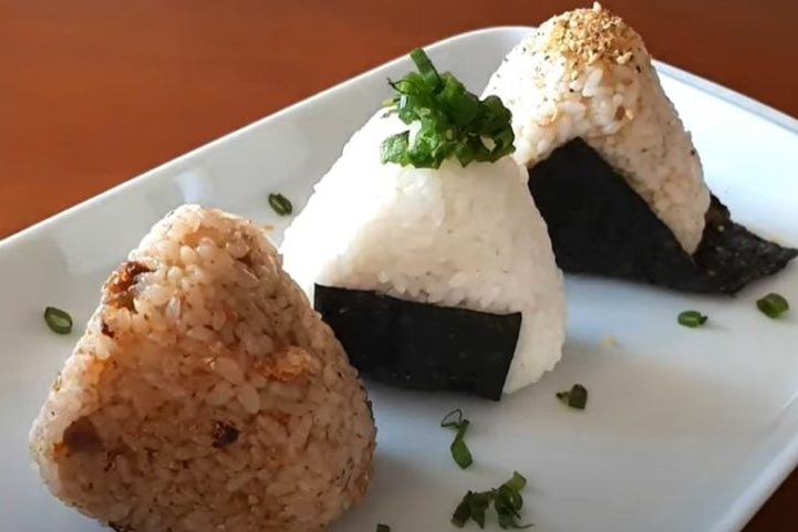 Onigiri: Bolinho de arroz recheado com diversos ingredientes, como salmão, atum, umeboshi ou furikake. Uma opção prática para lanches ou refeições rápidas. Reprodução: Flipar