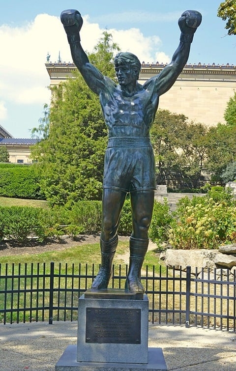 Sylvester Stallone, na pele do icônico personagem Rocky Balboa, também teve sua estátua inaugurada na Filadélfia, nos Estados Unidos. Reprodução: Flipar