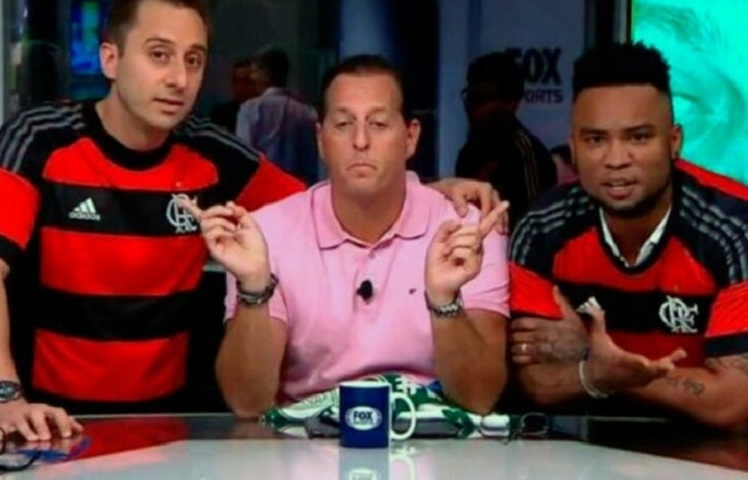 Os comentaristas Carlos Alberto e Fabio Azevedo vestiram a camisa do Flamengo e cantaram o hino do time durante o programa Fox Sports Rádio em 2019. Os dois comentaristas tinham apostados com outros colegas de bancada que o Rubro-Negro perderia o duelo contra o Vasco pela 15ª rodada do Brasileirão. Reprodução: Flipar