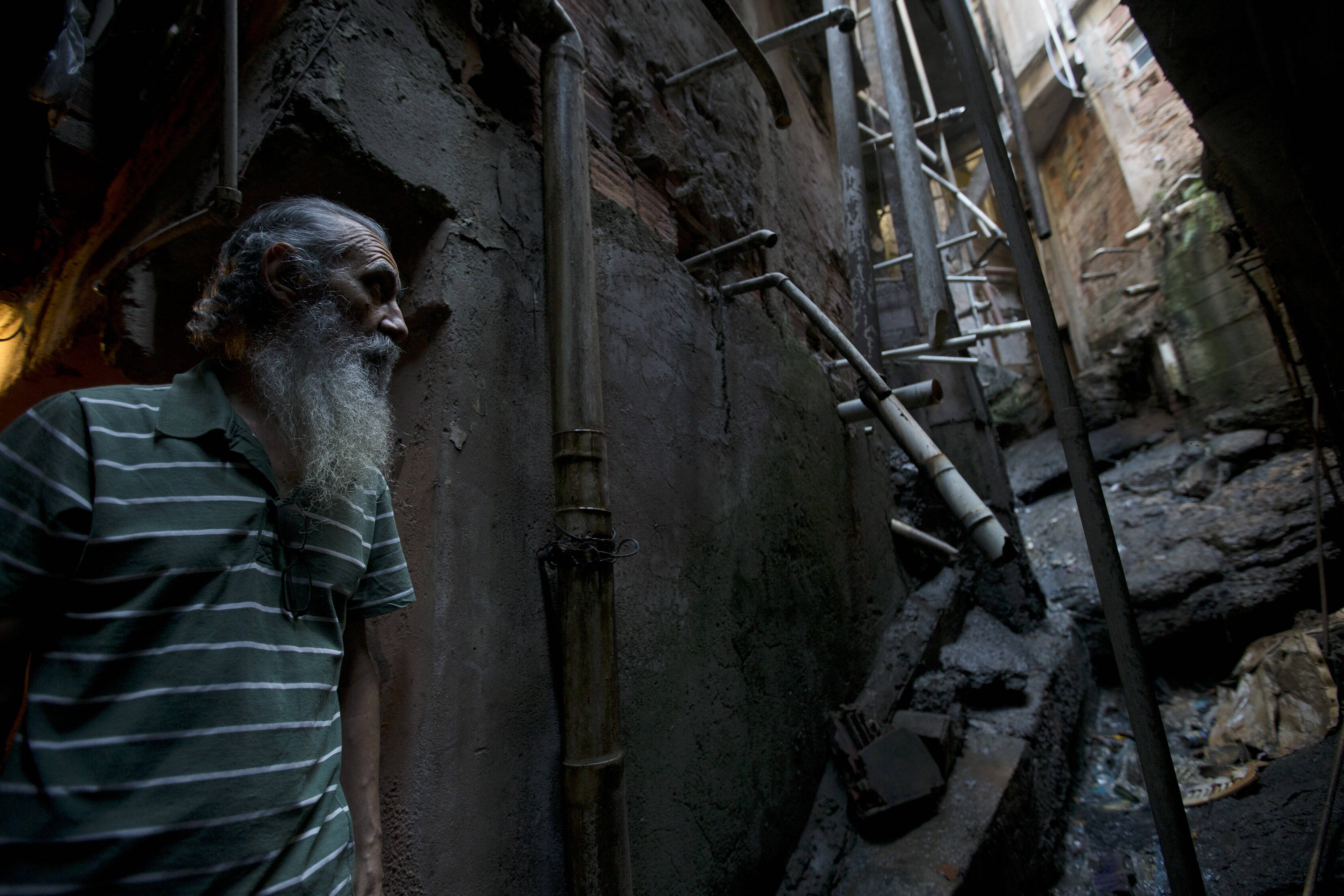 José Martins, de 68 anos, vê o esgoto a céu aberto na porta de sua casa na favela da Rocinha . Foto: Silvia Izquierdo/AP