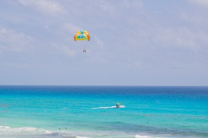 O parasailing é muito popular em destinos turísticos costeiros, como praias do Caribe, Mediterrâneo, Sudeste Asiático e até no Brasil. Reprodução: Flipar