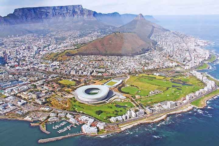 O Estádio da Cidade do Cabo fica na capital da África do Sul e foi uma das sedes oficiais da Copa do Mundo de 2010 e do Campeonato das Nações Africanas de 2014. Localiza-se no bairro de Green Point, entre a Montanha da Mesa e o Oceano Atlântico. Sua capacidade máxima é de 55.000 espectadores. Reprodução: Flipar